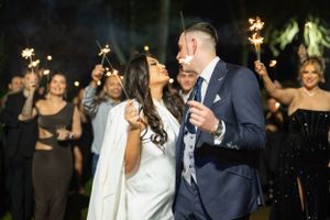 Wedding party celebrating outdoors with sparklers creating a festive ambiance.