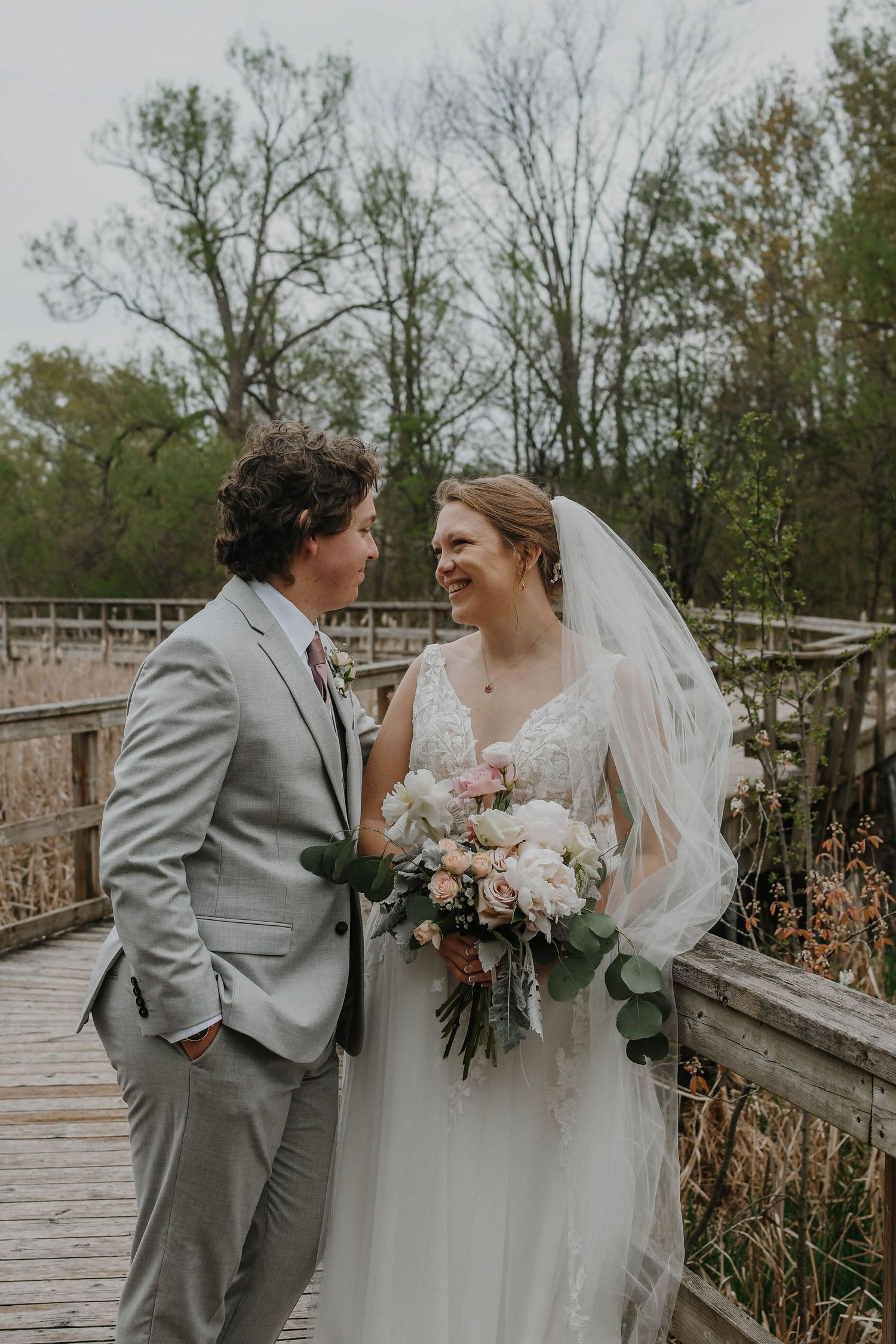 A couple shares a joyful moment together on a wooden boardwalk surrounded by autumn trees.