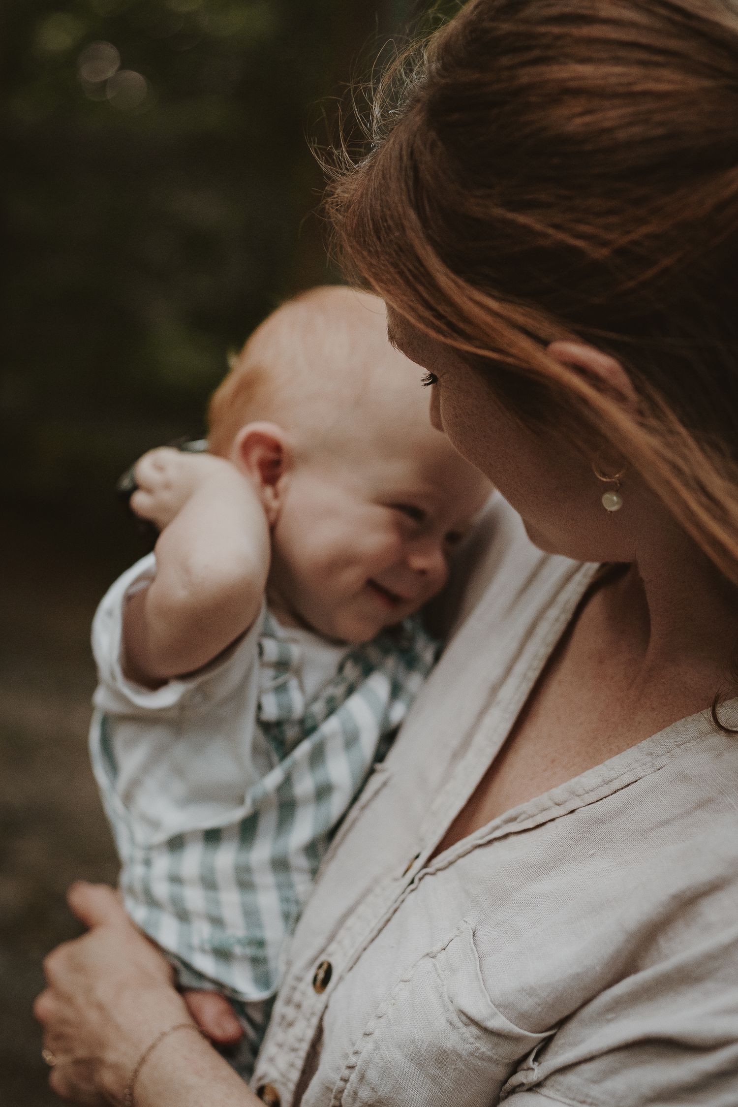 An intimate moment between mum and laughing baby captured in warm, moody tones during a family session on Otley Chevin.