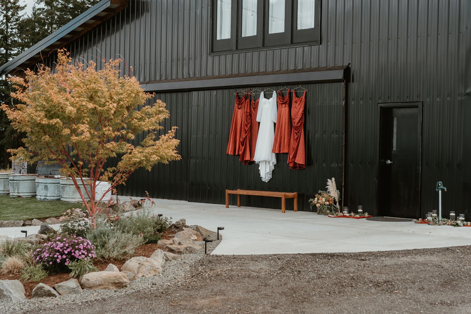 Wide shot of bride & bridesmaid dresses hanging on new rustic barn.