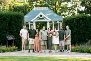 Large family group poses together in front of a garden gazebo outdoors.