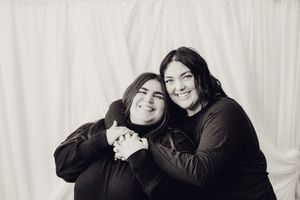 Two women hugging and smiling together in a black and white portrait photo.