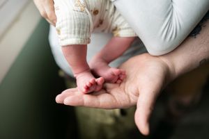 Close-up of a newborns tiny feet resting gently in a parents cupped hands.