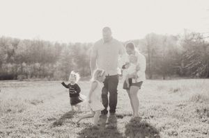 Black and white family photo with parents and two young children in open field.