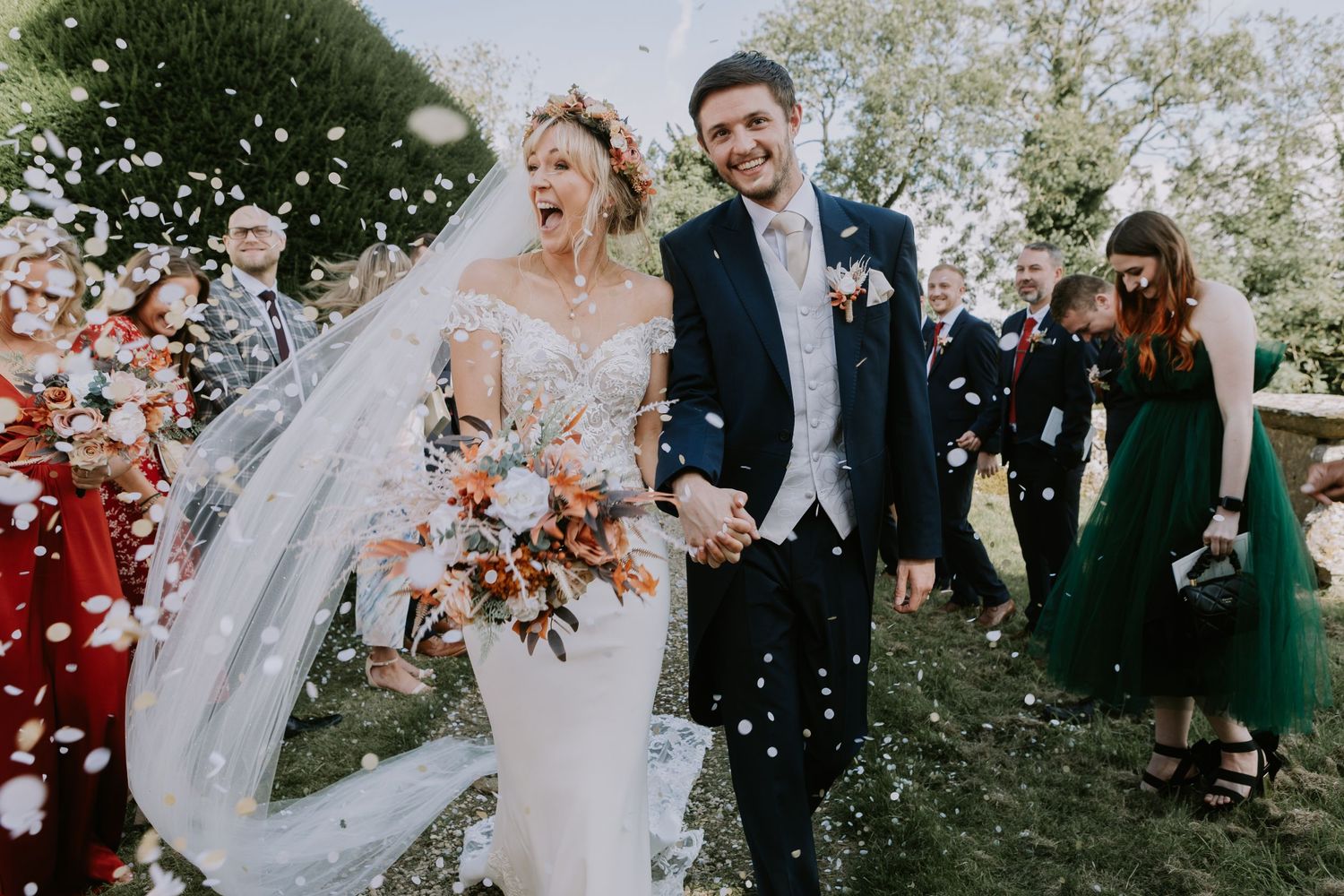 A celebration with confetti throws and fluttering wedding veil in an outdoor garden setting.
