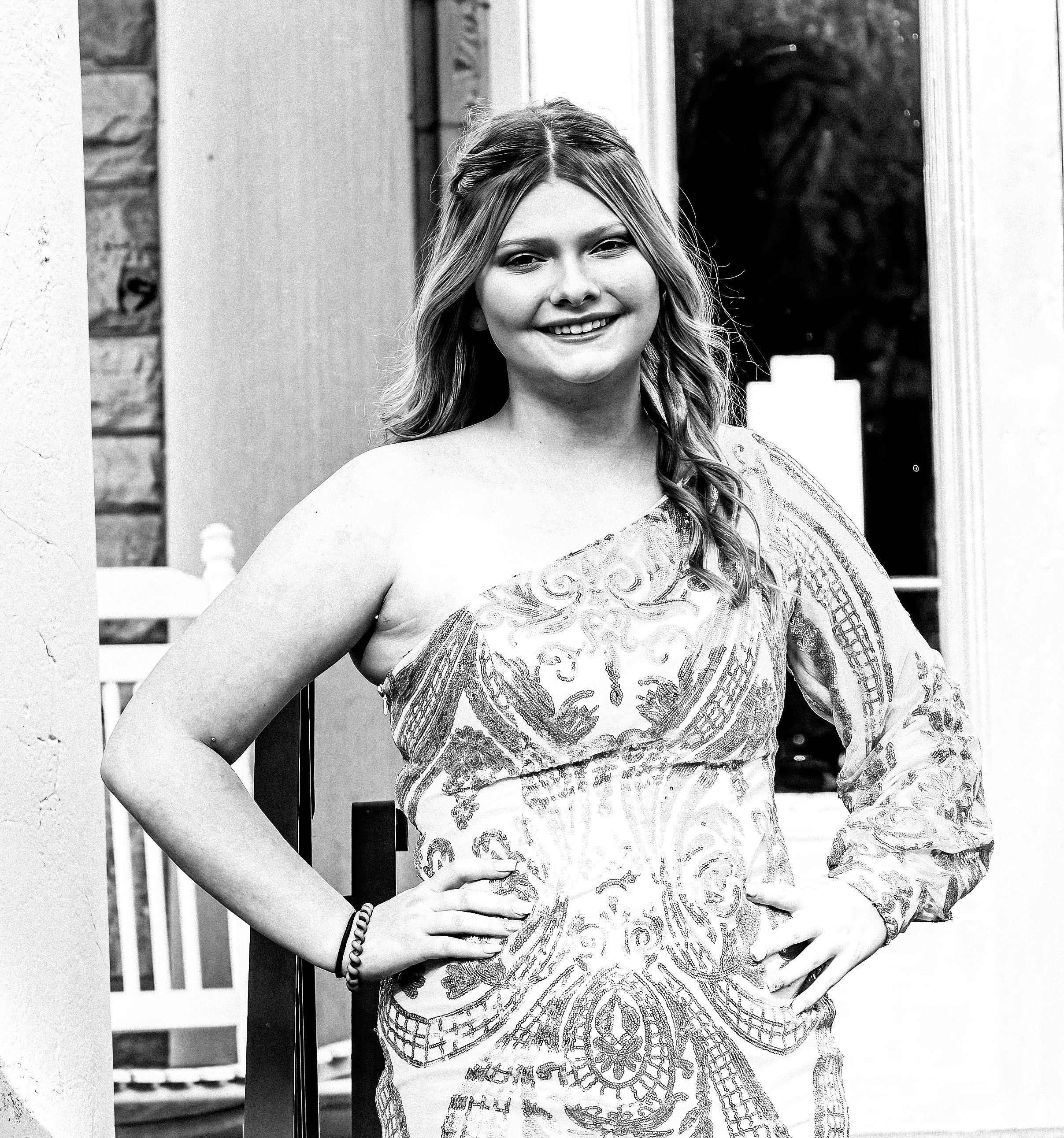 A person poses in an elegant white patterned dress with one-shoulder design outdoors.
prom 
riverside