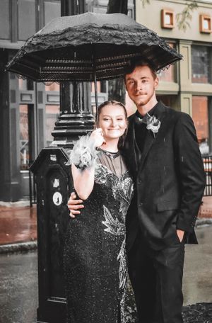 A couple poses under a black lace umbrella in formal attire on a rainy day near a vintage lamp post.
prom 
riverside