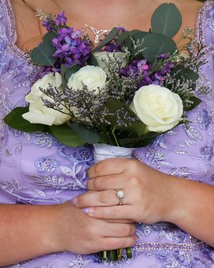 A close-up of hands holding a wedding bouquet with white roses and purple flowers against a lavender dress.
prom 
riverside