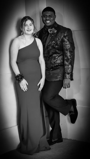 A formal couple poses in black and white, wearing elegant evening attire.