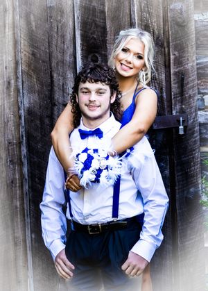 A couple in coordinated blue and white formal attire pose together against a rustic wooden backdrop.
prom 
riverside