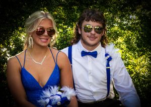 Couple in formal wear pose outdoors with sunglasses and blue attire against greenery.
prom 
riverside