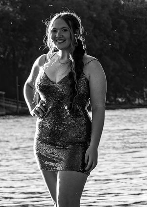 Black and white portrait of someone in a sequined dress posing by water at sunset.
prom 
riverside