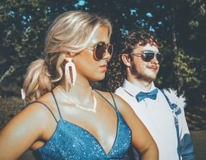Formal portrait of couple in blue and white attire with sunglasses in garden setting.
prom 
riverside