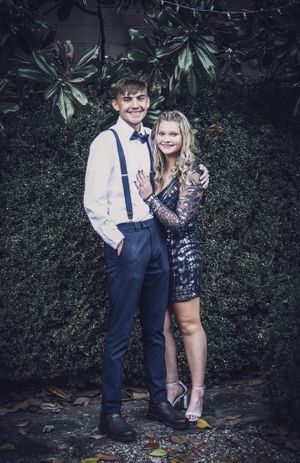 Formal couple pose against dark foliage wall with string lights in moody lighting.
prom 
riverside