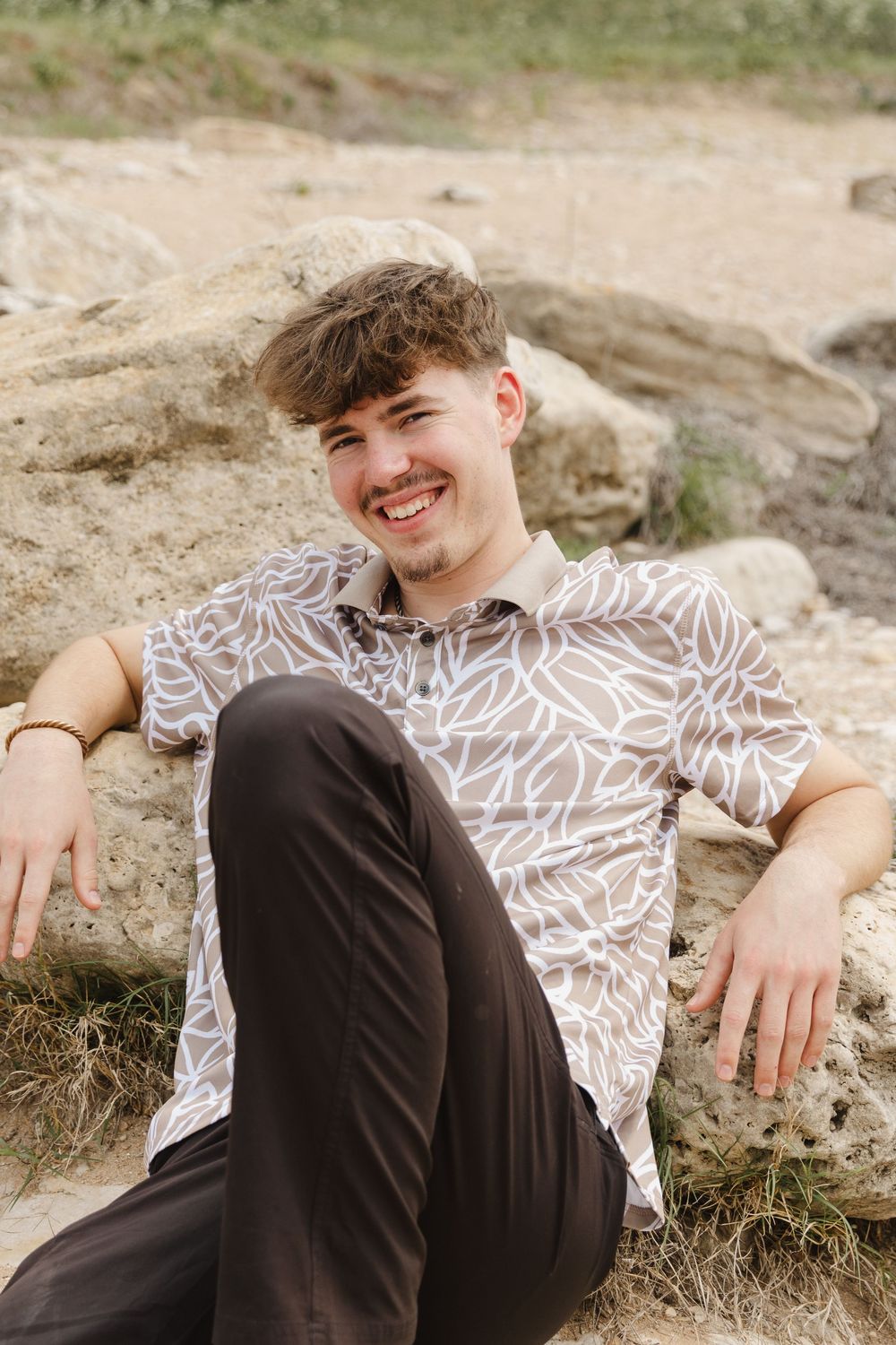 Someone relaxing outdoors in a floral print shirt and dark pants against a desert landscape.