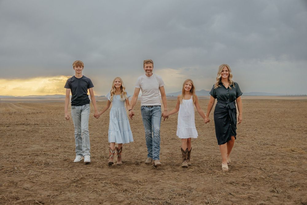 Family walking together across an open desert landscape at dusk.