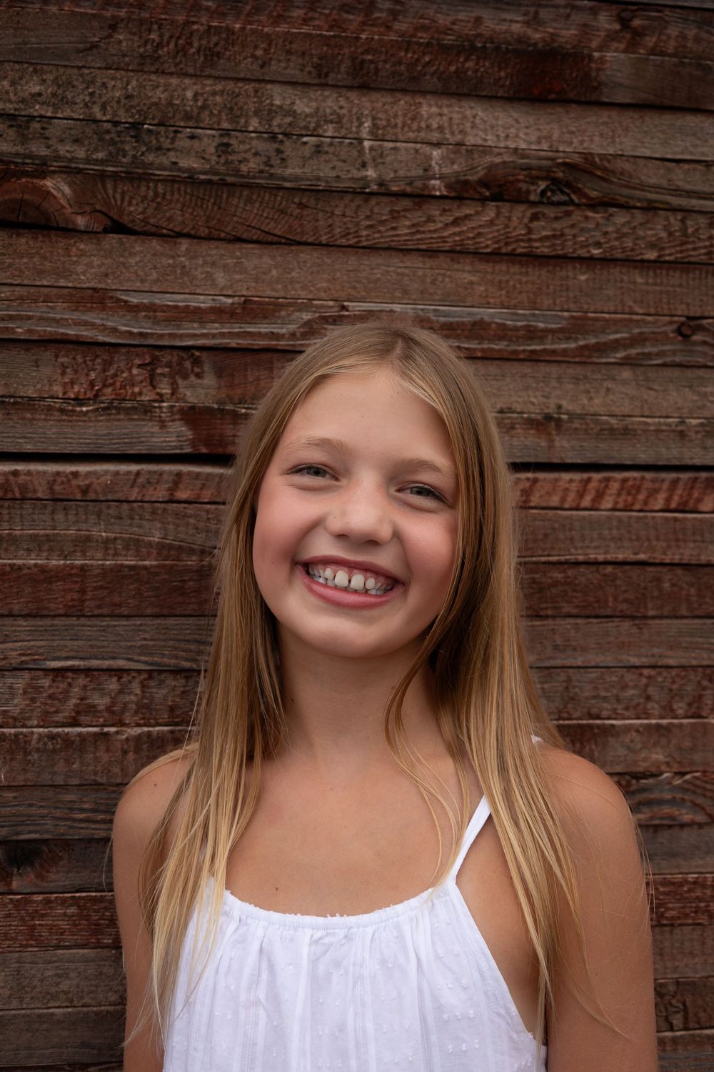 A series of close-up shots showing bright smiles against a rustic wooden wall background.