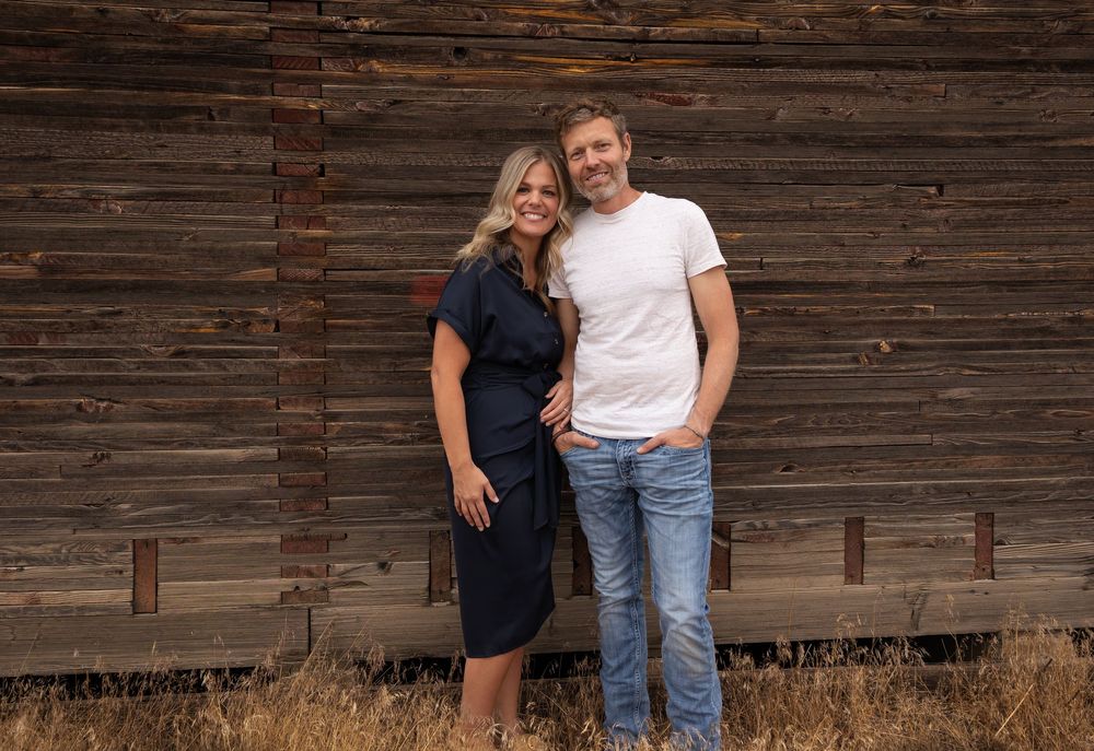 Family portrait session in front of a weathered wooden barn wall.