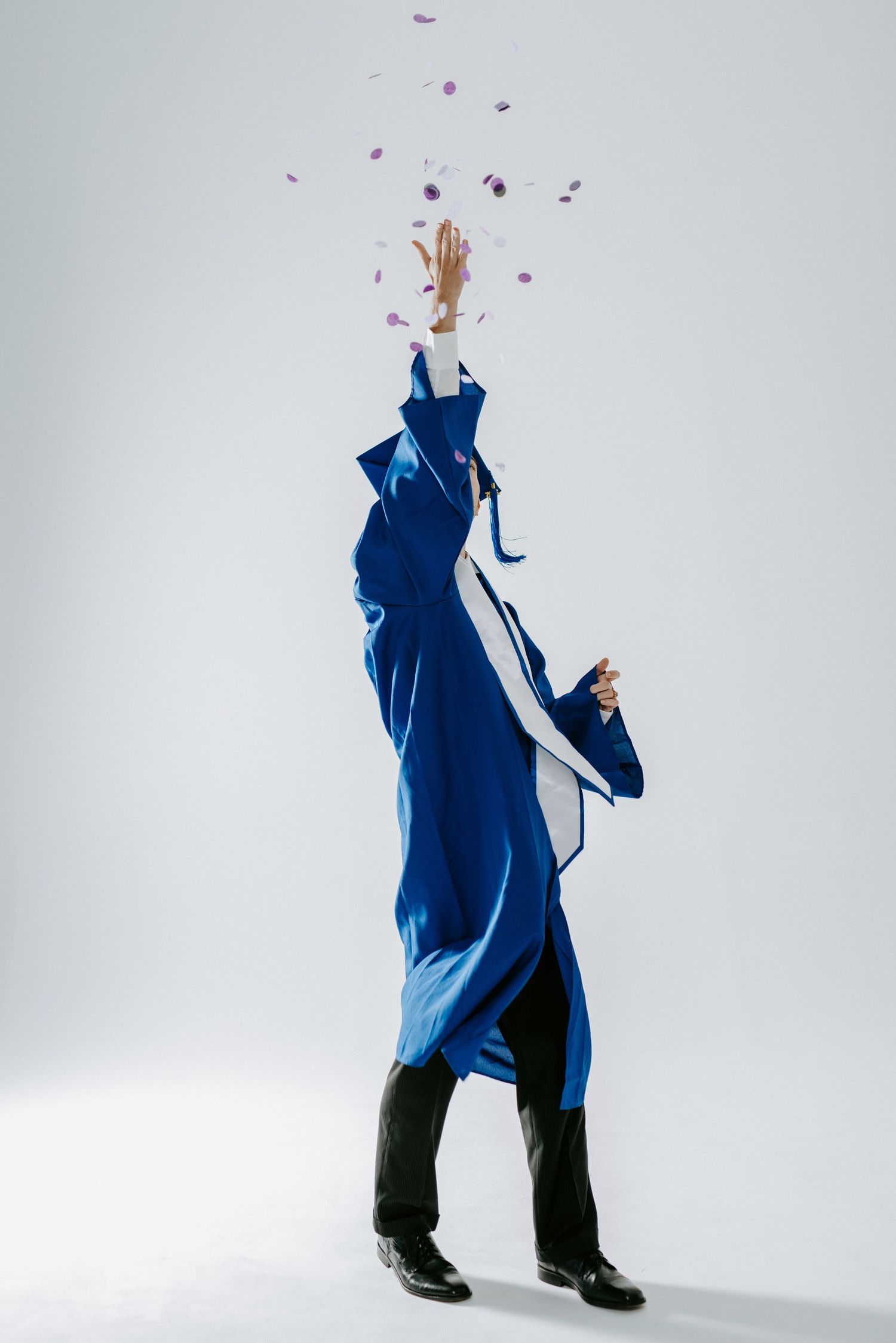 A figure in a blue coat dances and twirls while rose petals fall through the air against a white background.