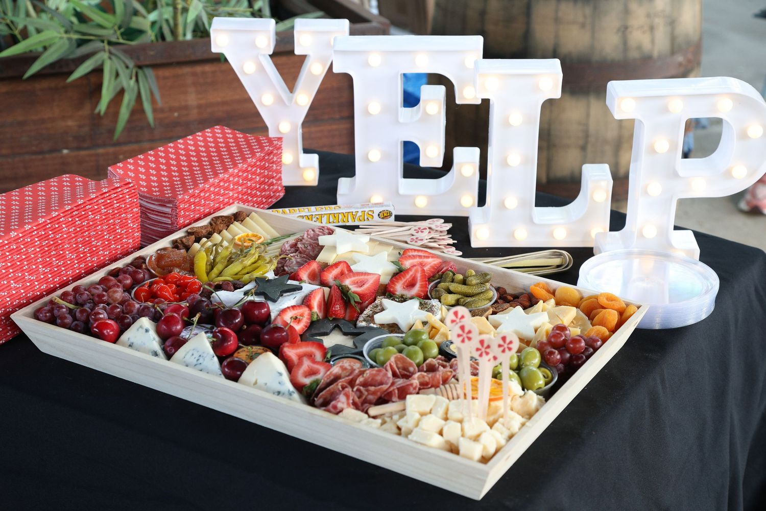 A long grazing table filled with charcuterie, cheeses, fruits and decorative white letter signs for a special event.