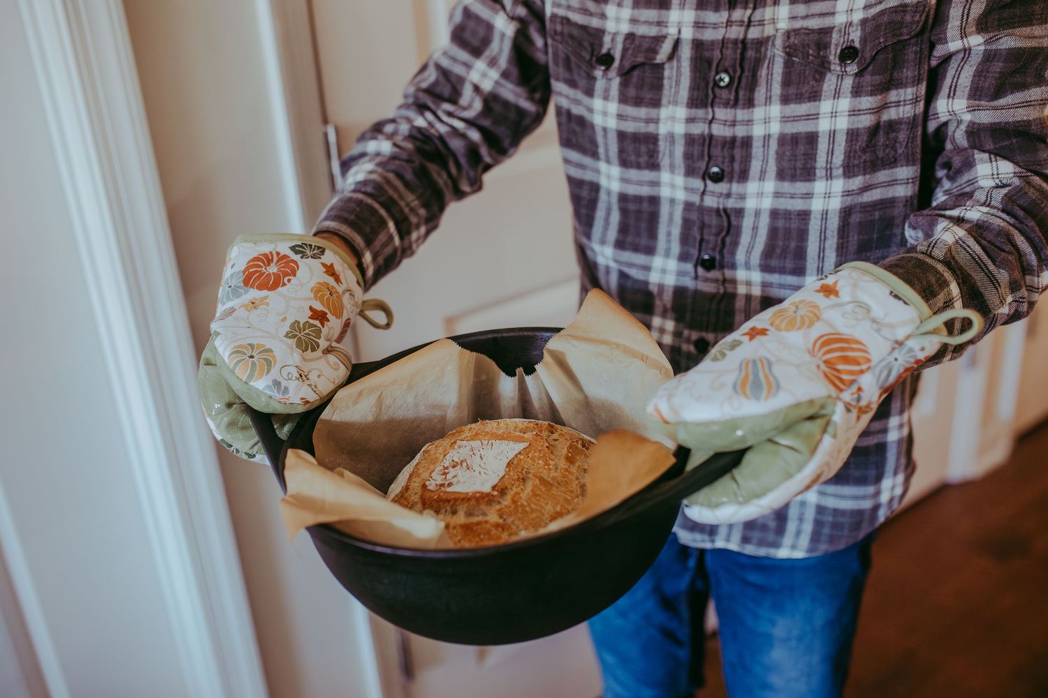 A person in a plaid shirt baking bread a pan with oven mitts on. Lifestyle photography. Whitney Popp Arizona photographer.