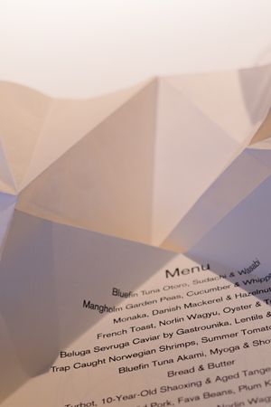Elegant restaurant menu showing multiple courses with French and Nordic dishes in soft focus.