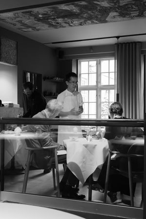 Interior view of a fine dining restaurant with white tablecloths and large windows.
