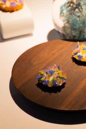 Decorative wooden plate garnished with colorful edible flowers and artistic presentation.