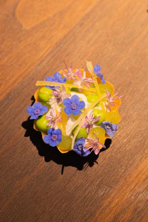 Colorful edible flowers arranged on a wooden surface with purple and yellow blooms.