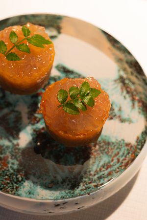 Orange glazed appetizers garnished with fresh herbs served on a turquoise ceramic plate.
