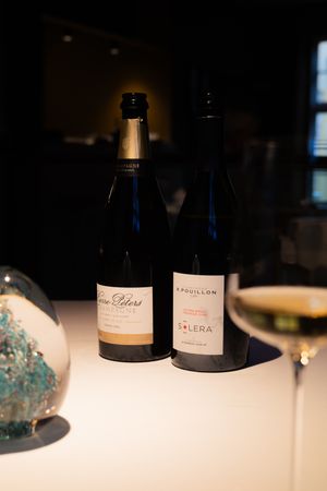 Wine bottles displayed on a white tablecloth in a dimly lit restaurant setting.