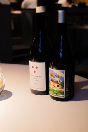 Collection of wine bottles with artistic labels displayed on white tablecloth.