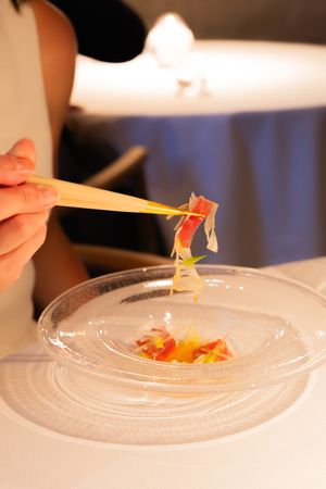Close-up sequence of small colorful garnishes being delicately placed on a white plate.