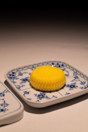 Yellow macaron displayed on traditional blue and white patterned china plate.
