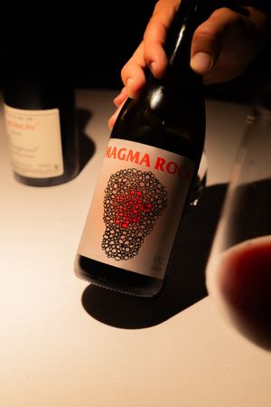 A bottle of Magma Rock wine with distinctive red dotted skull design on the label.