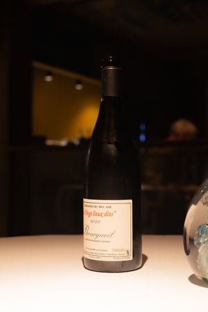 Wine bottles arranged on a white surface with soft lighting and glassware.