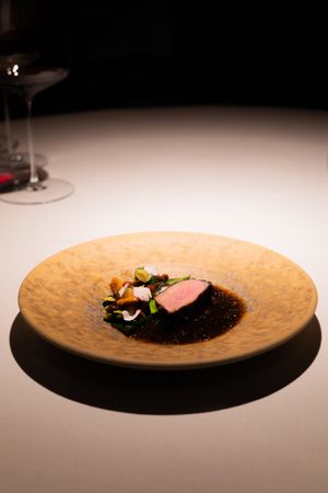 Artistically plated dish on a textured ceramic plate with dark background.