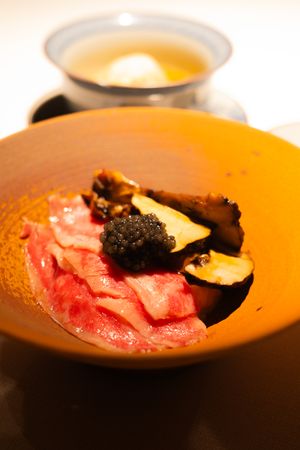 Raw seafood or sashimi served on an orange-tinted plate in dramatic lighting.