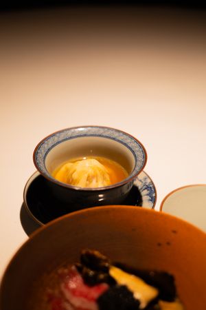 A steaming dumpling soup served in an ornate blue and white Chinese bowl.