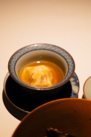 Close-up of a traditional Asian soup dumpling floating in golden broth.