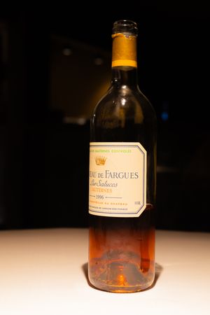 Vintage wine bottle illuminated against a dark background on a white surface.