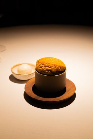 Minimalist presentation of brown-colored desserts on wooden plates against a light gradient background.