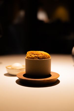 Sequence showing a round orange-colored dish served in a dark ceramic bowl.