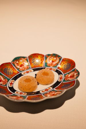 Traditional Japanese Imari plate with orange and red floral patterns displaying small round dishes.