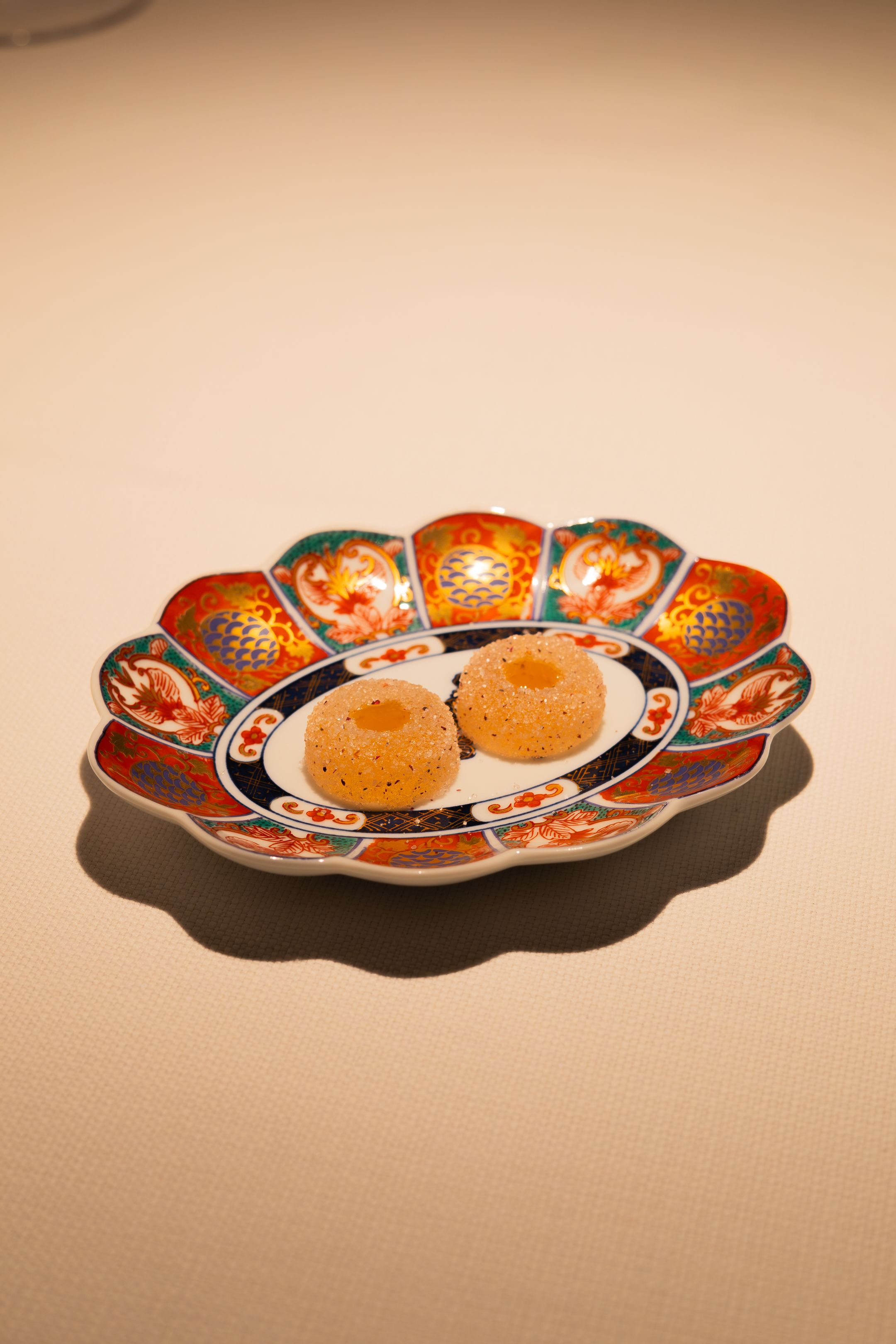 A decorative orange and black Japanese porcelain plate with floral patterns shown from multiple angles.