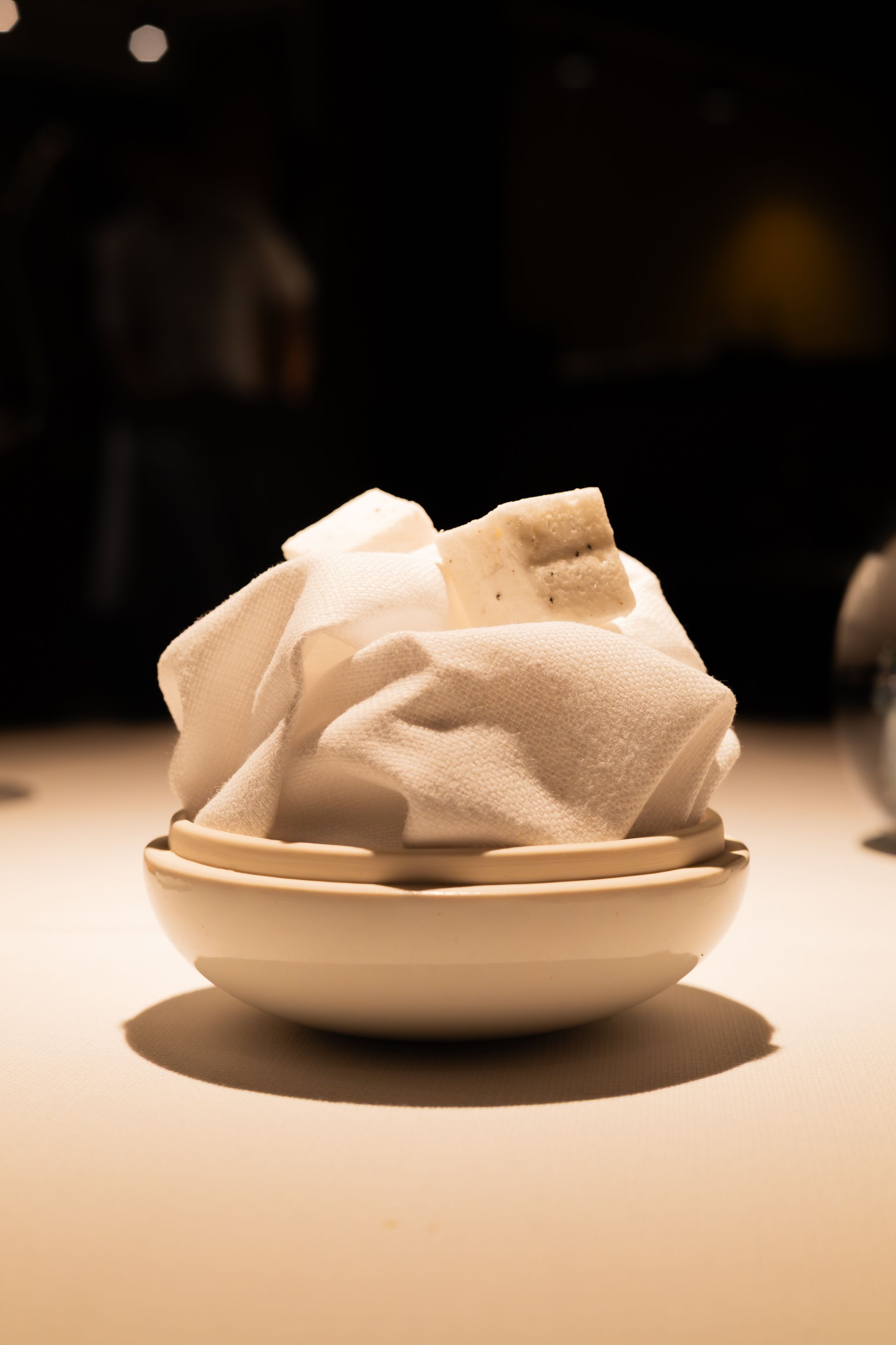 A series of white napkins folded in different ways on white plates shown in a progression from left to right.
