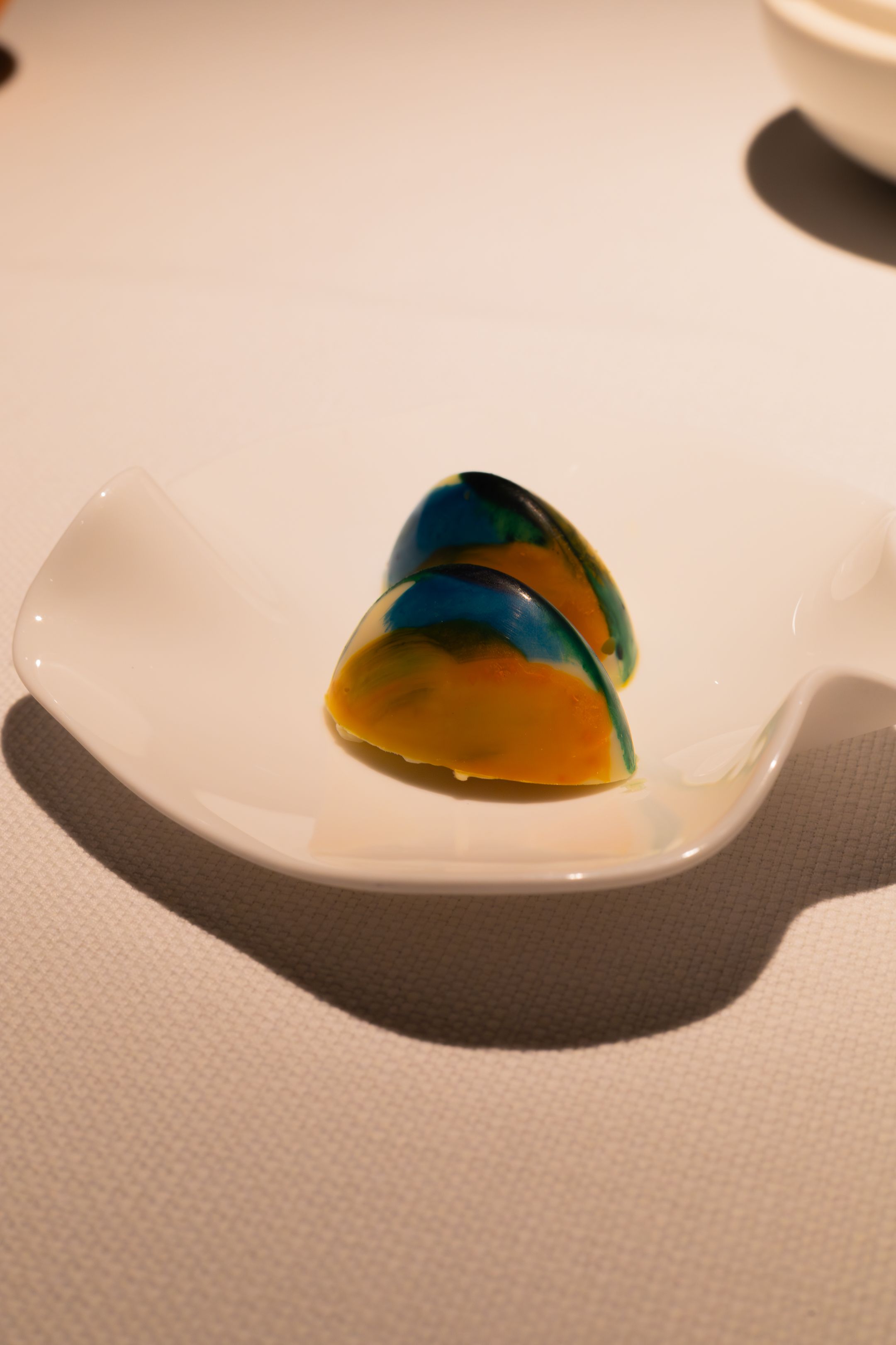 A series of four sequential photos showing a yellow and blue pill casting a shadow on a white textured surface.