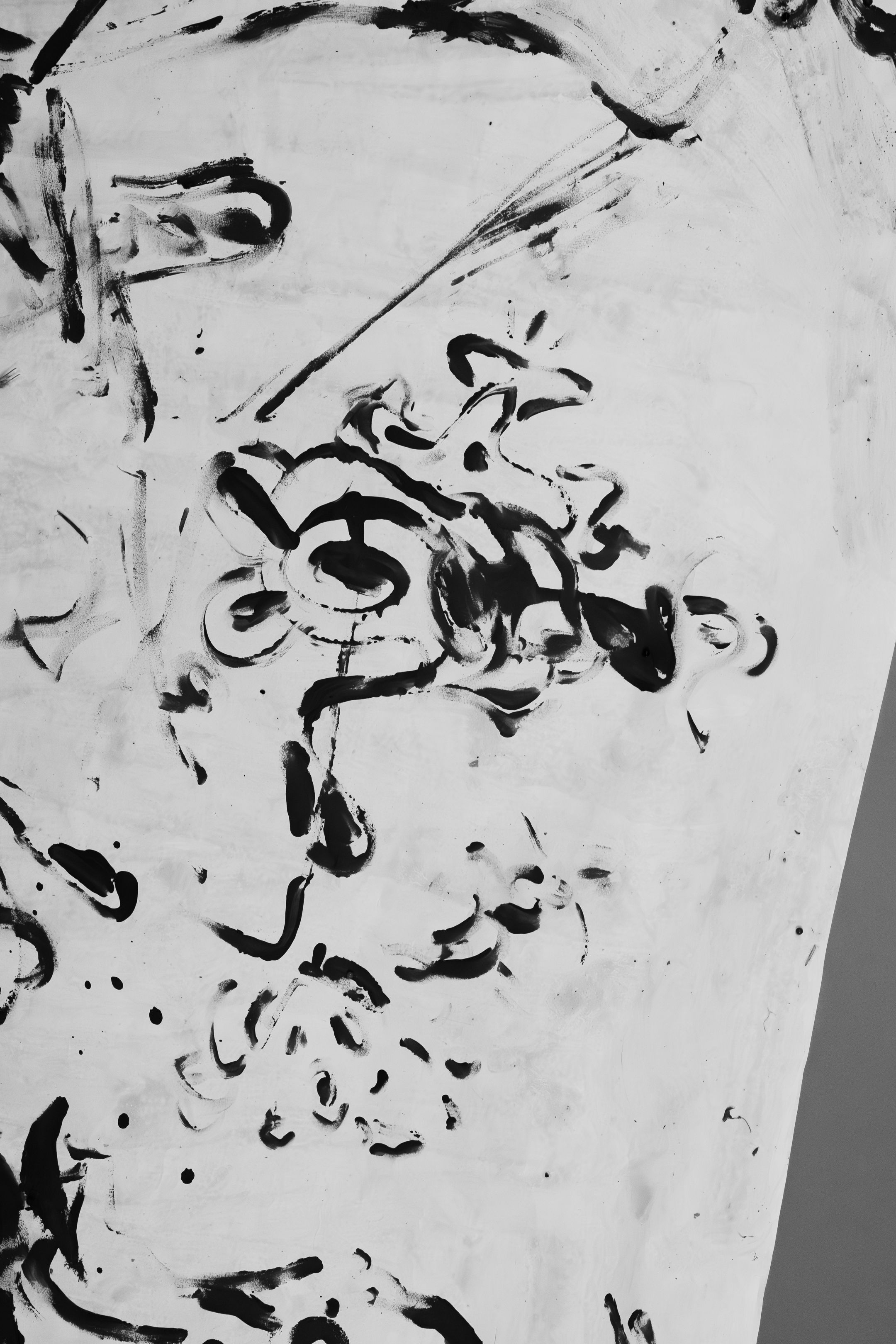 Abstract black ink calligraphy marks on white paper creating an artistic pattern.