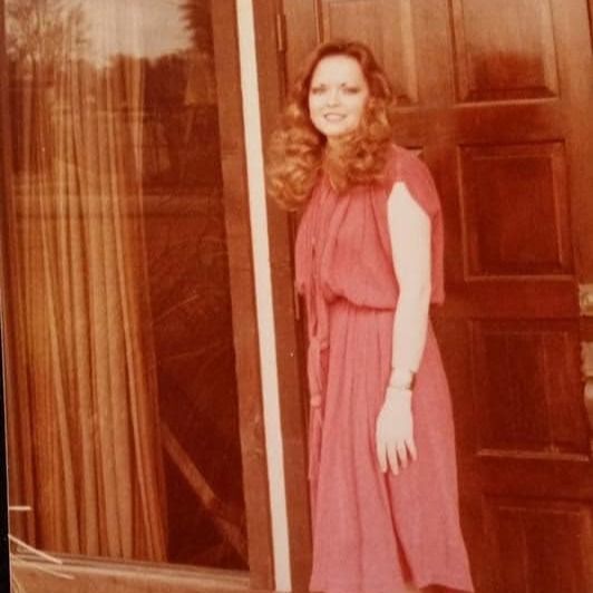 Four photos in a sequence show a person in a pink or salmon-colored dress standing against a brown curtained backdrop.