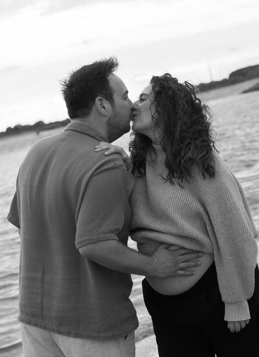 Romantic couple embracing on a beach at sunset in black and white.